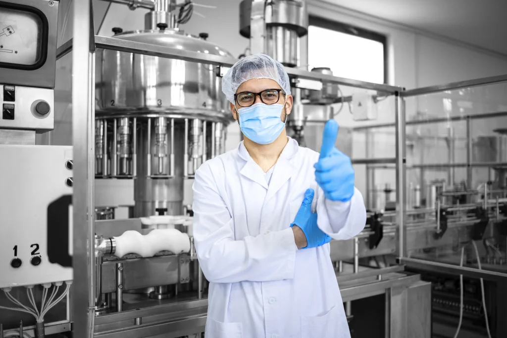 Confident engineer in lab attire gives a thumbs up conveying a positive signal in a modern, automated production environment. This image represents CTE's expertise and commitment to delivering customised and future-proof automation solutions through collaborative partnerships and in-depth expertise.